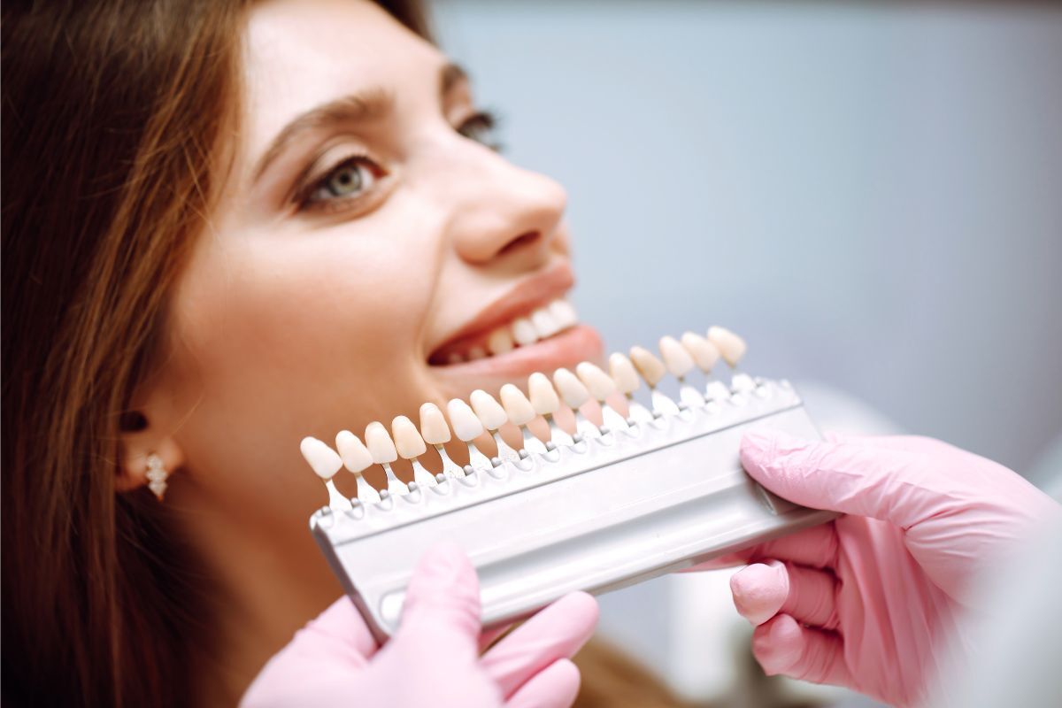 Woman examining tooth shade guide with dentist during cosmetic bonding consultation.