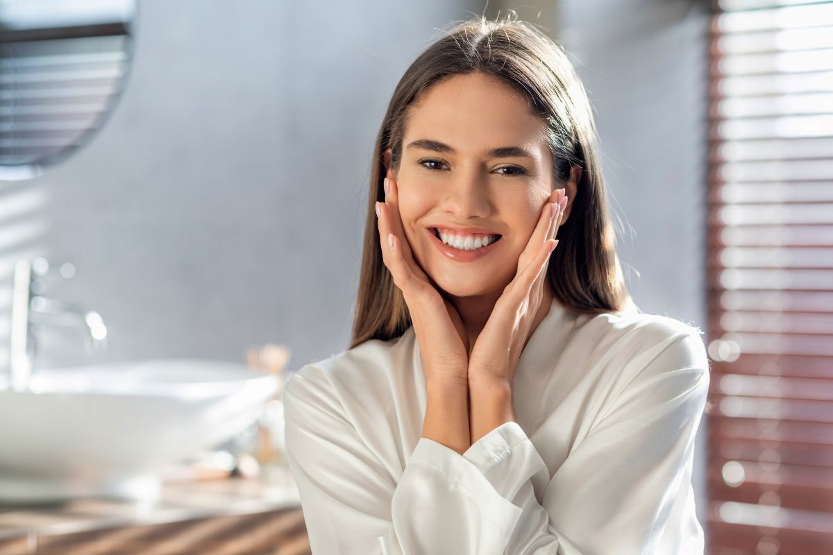 Smiling woman touching her face displaying results of dental veneers or bonding treatment in Carmel.